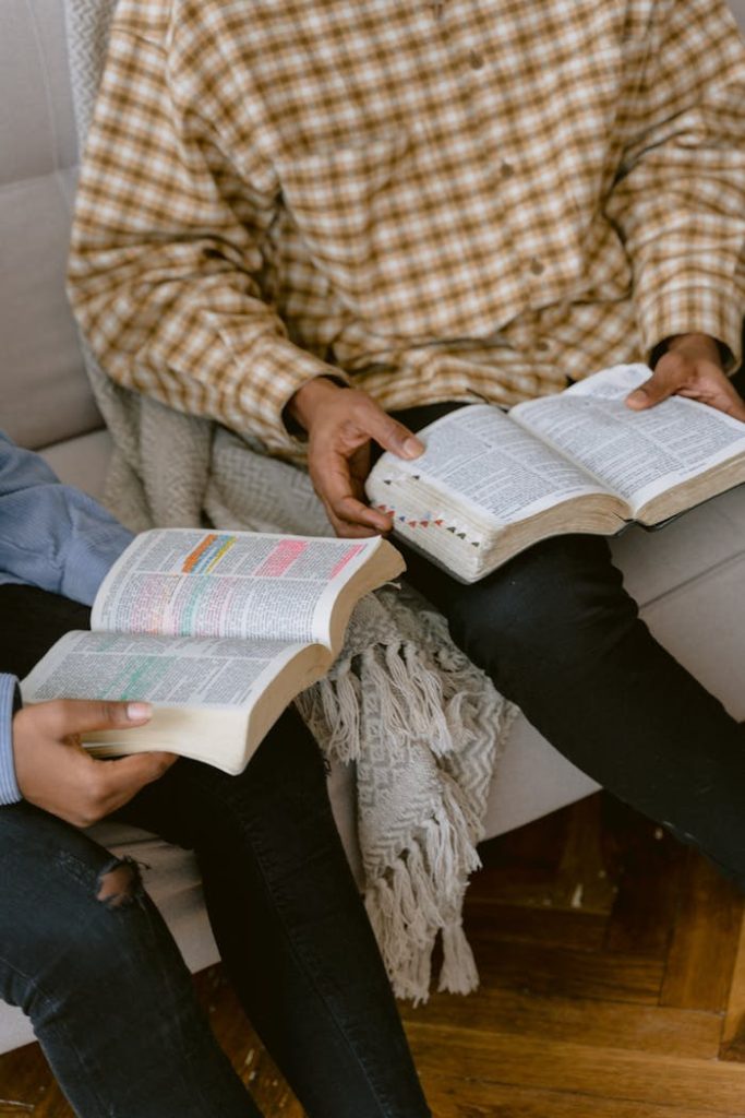 two-people-reading-bible-while-sitting-on-a-sofa-6860819 Two individuals sitting on a sofa reading and discussing the Bible indoors.